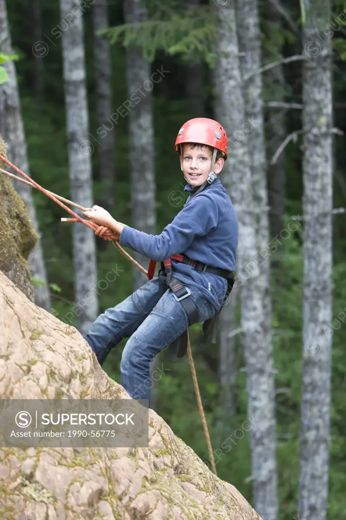 A young boy rappells down a cliff_face at Horne Lake´s outdoor climbing area, near Qualicum Beach, Central Vancouver Island, British Columbia, Canada.