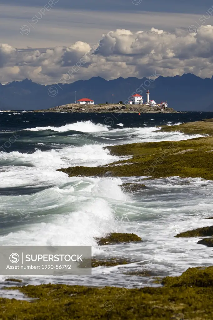 The lighthouse on Entrance Island stands out against a mountainous west coast backdrop amid a crashing surf onto Gabriola Island, Southern Gulf Island...