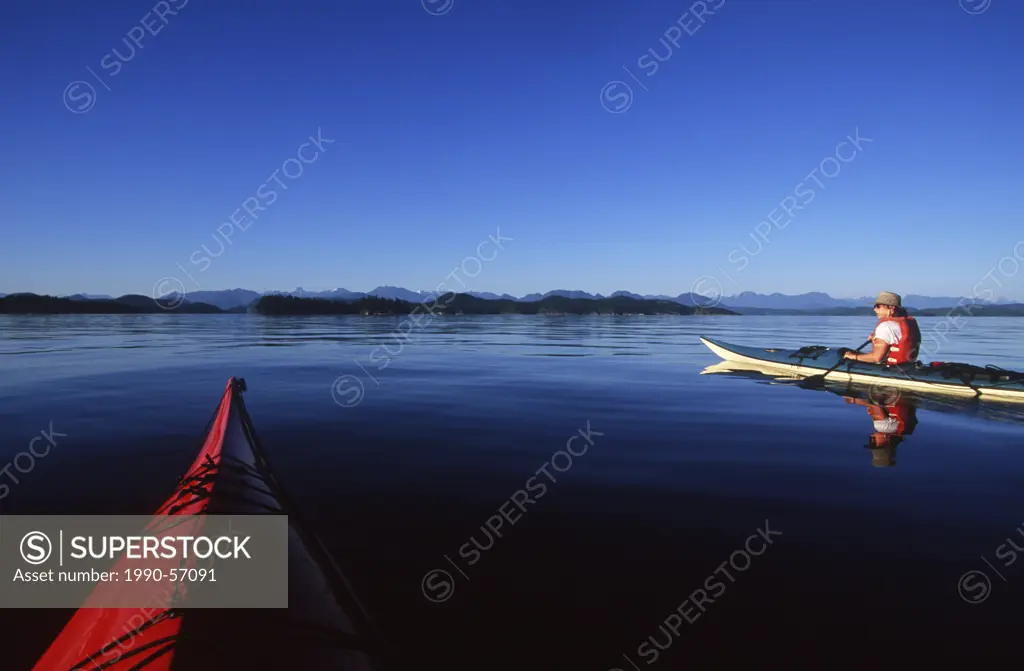 2 kayakers paddle to Breton Islands on summer evening, Quadra Island, Vancouver Island, British Columbia, Canada.