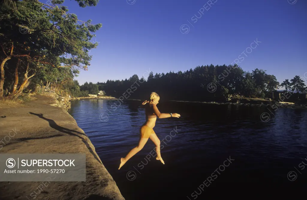 Malaspina Galleries, Gabriola Island, Young girl jumping from sandstone ledge, Vancouver Island, British Columbia, Canada.