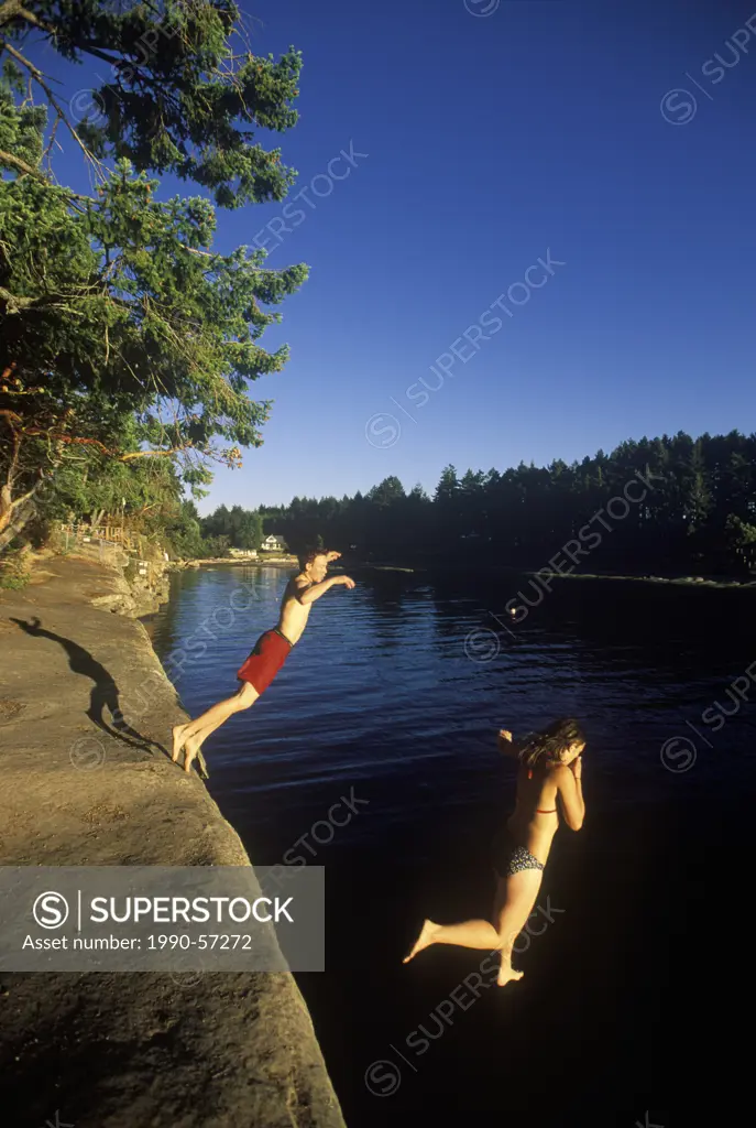 Malaspina Galleries, Gabriola Island, Young couple jumping from sandstone ledge, Vancouver Island, British Columbia, Canada.