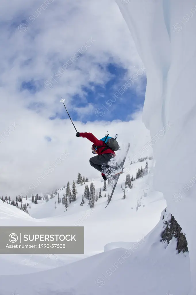 A male skier catches some air into fresh powder while ski touring at, Sol Mountain Lodge, Monashees, British Columbia, Canada