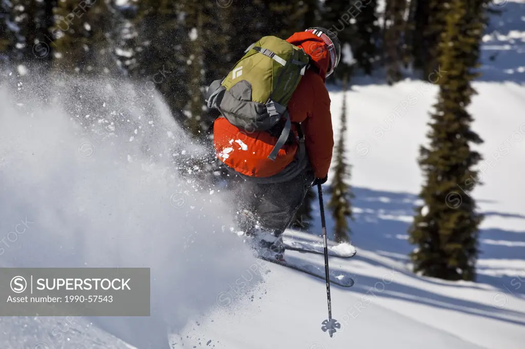 A male skier catches some air into fresh powder while ski touring at, Sol Mountain Lodge, Monashees, British Columbia, Canada