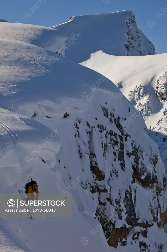 A male skier drops off a cornice in the, Kicking Horse Backcountry, Golden, British Columbia, Canada