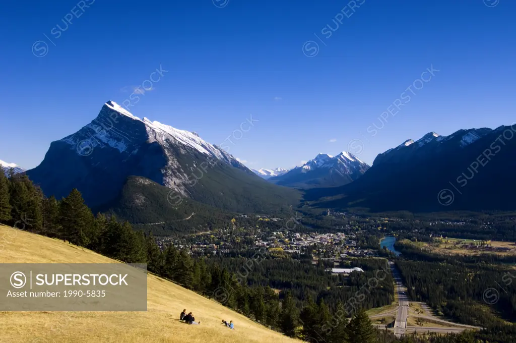 Visitors in meadow overlooking Banff townsite from Mt  Norquay, Banff National Park, Alberta, Canada