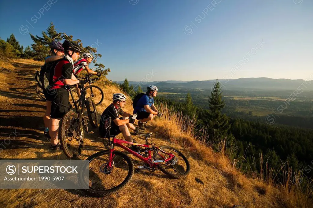Mountain bikers at Viewpoint on Mt  Tzuhalem overlooking Duncan and the Cowichan Valley, Vancouver Island, British Columbia, Canada