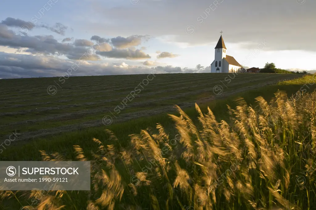 Sunset over hay field and St Mary´s church near Pincher Creek, Alberta, Canada.
