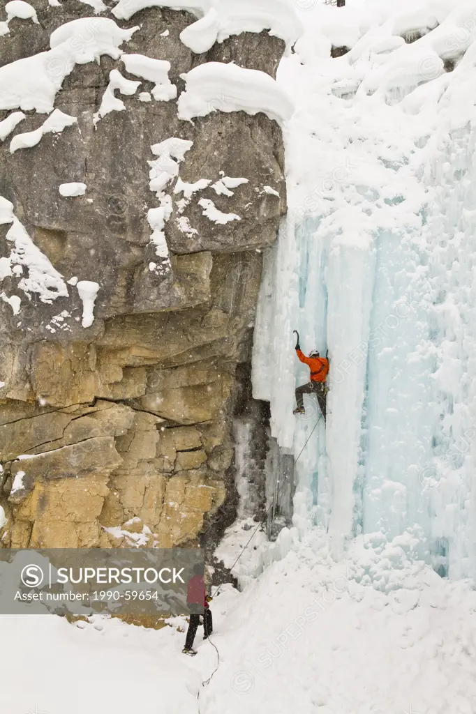 Young man ice_climbing while other man belays him in Banff National Park near Banff, Alberta, Canada.