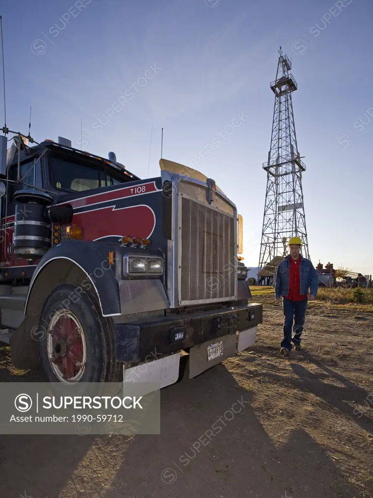 Truck parked in front of oil drilling derrick.