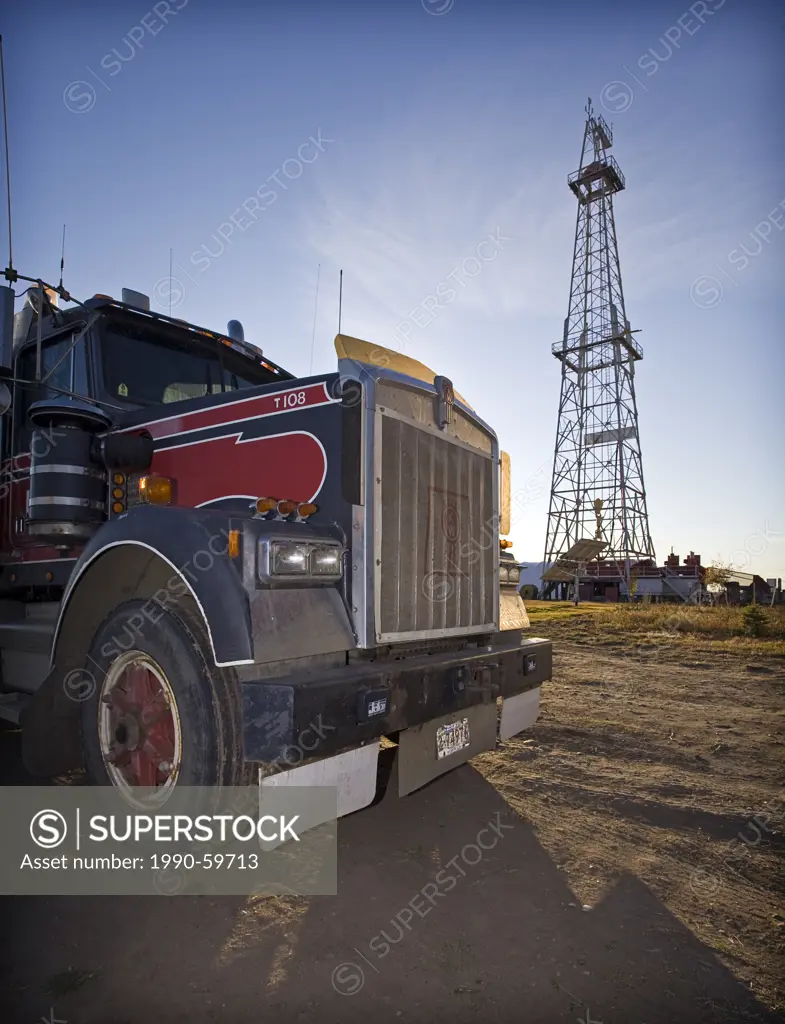 Truck parked in front of oil drilling derrick.