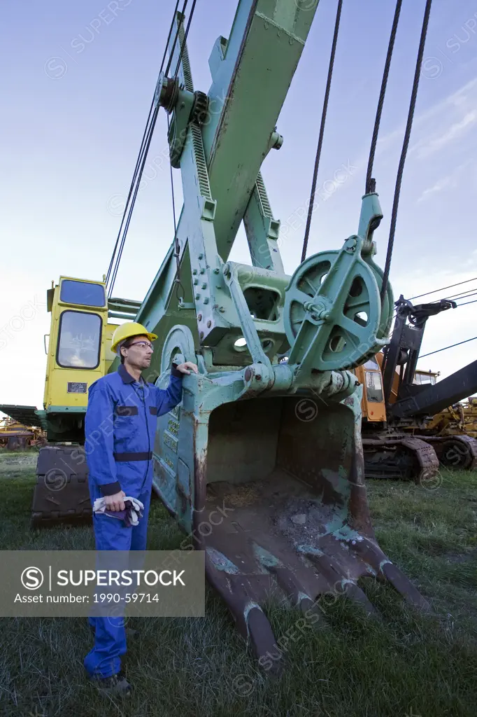 Heavy equipment operator standing next to excavating shovel.
