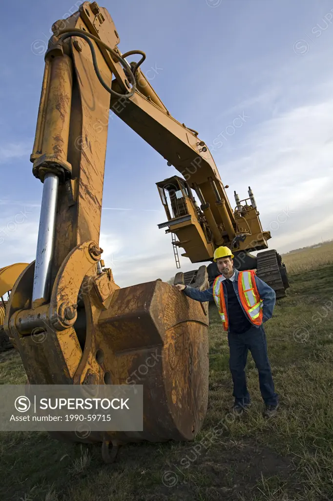 Heavy equipment operator standing next to excavating machine.