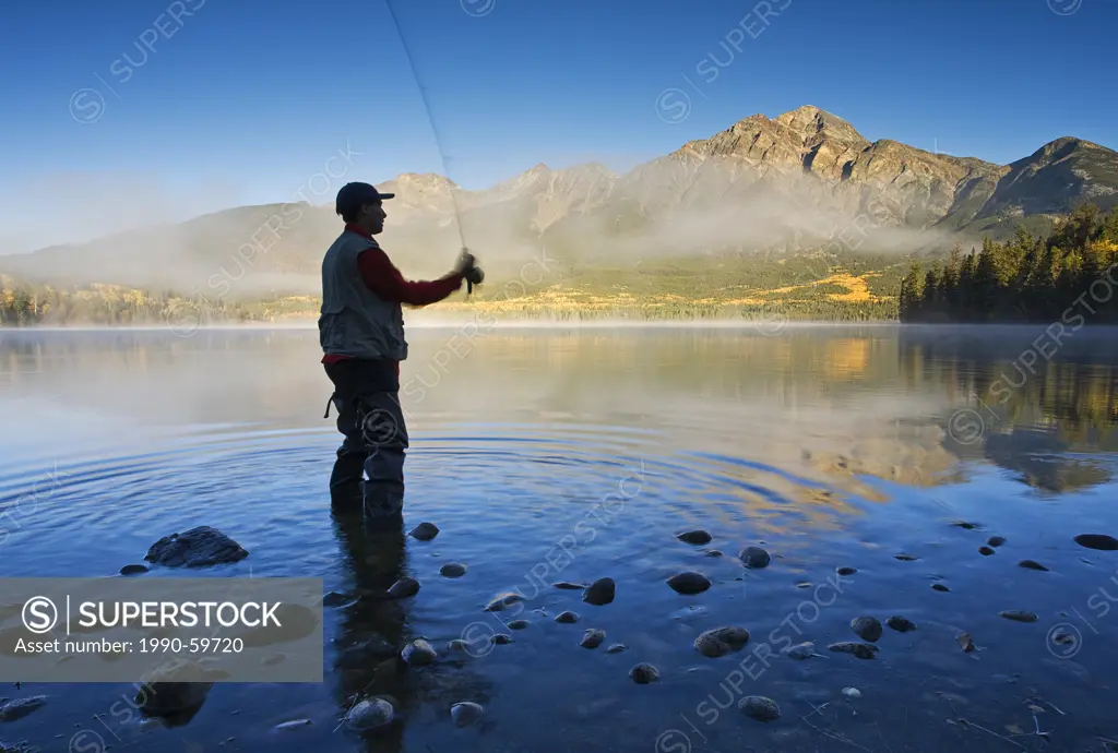Middle age male fly fishing in Pyramid Lake, Jasper National Park, Alberta, Canada.