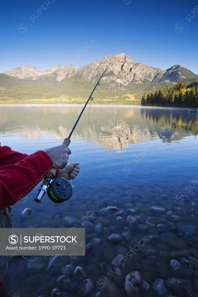 Close up hand on fishing rod at dawn, Pyramid Lake, Jasper National Park, Alberta, Canada.