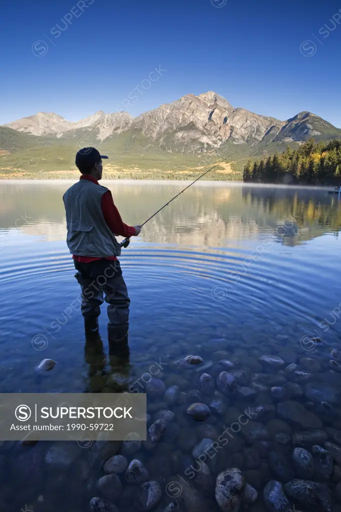 Middle age man fly fishing at Pyramid Lake, Jasper National Park, Alberta, Canada.