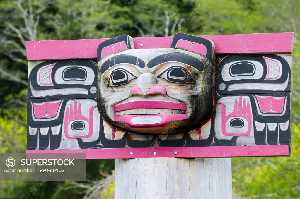 A weathered rectangular bear faced totem with thunderbirds on each side at a burial ground in Alert Bay on Cormorant Island near Vancouver Island, BC.