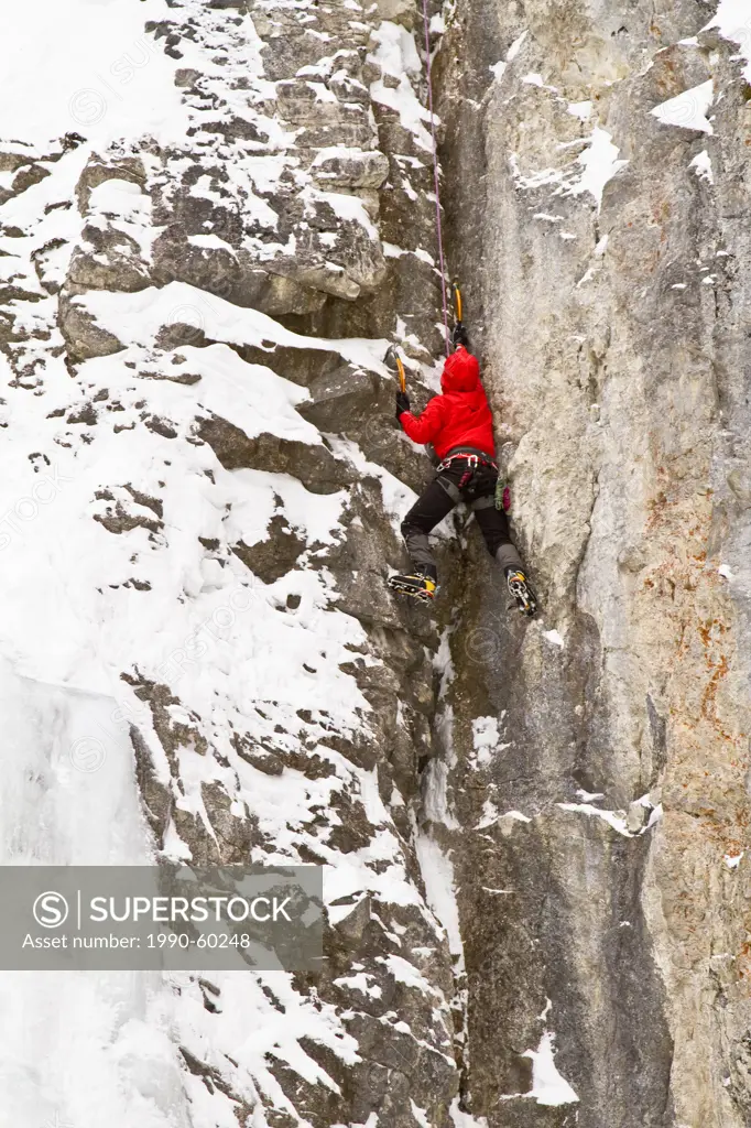 Young man climbs a mix of ice and rock while ice_climbing in Banff National Park near Banff, Alberta, Canada.