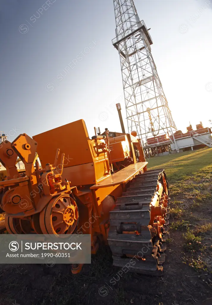 Earth moving equipment in front of a oil drilling rig, Alberta, Canada.