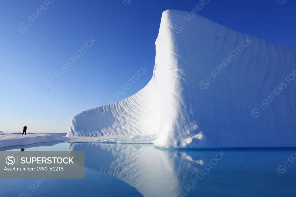 A tourist takes a picture of an iceberg in Nunavut, Canada in the Canadian Arctic