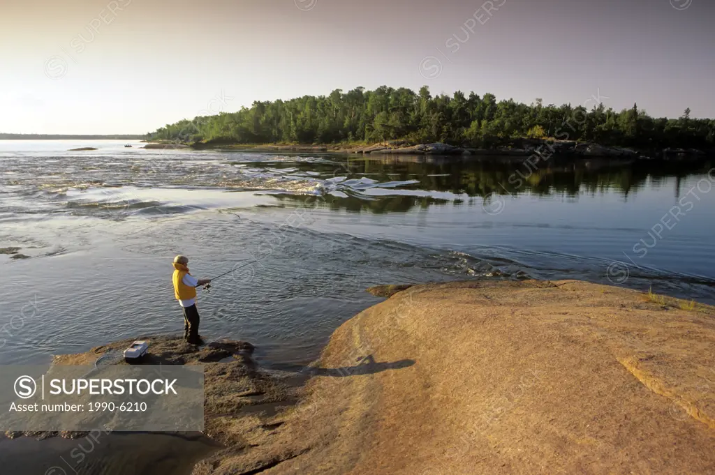 Boy fishing along Winnipeg River, Whiteshell Provincial Park, Manitoba, Canada