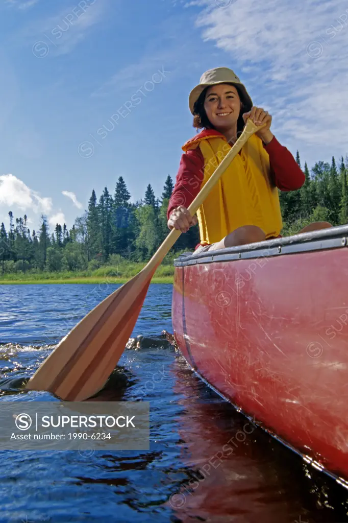 Young woman canoeing on the Whiteshell River, Whiteshell Provincial Park, Manitoba, Canada