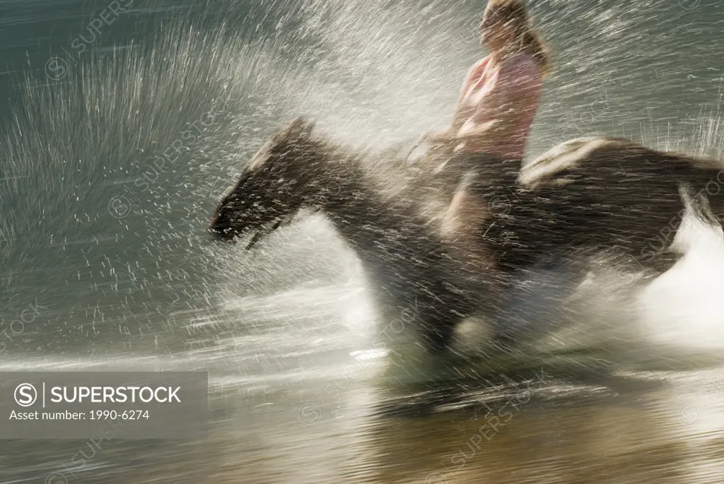 Woman riding horseback with no saddle on the shoreline of Tatlayoko lake, British Columbia, Canada