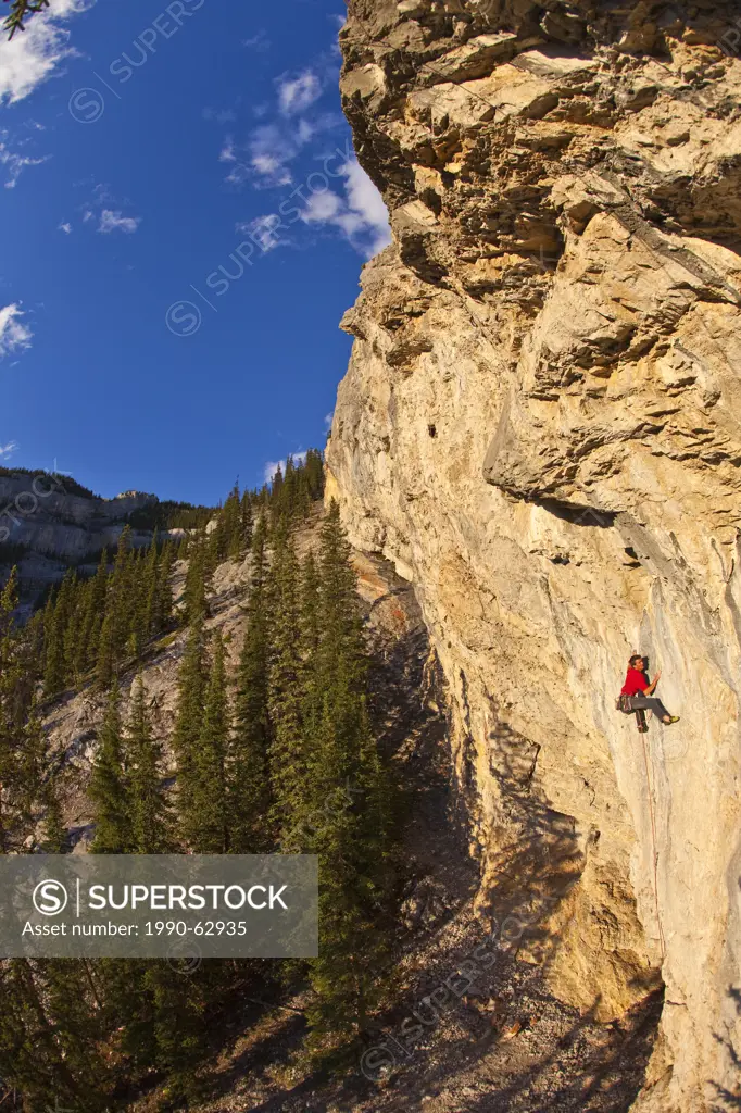 A man climbs the sport route Fire in the Sky 12b at sunset, Echo Canyon, Canmore, Alberta, Canada