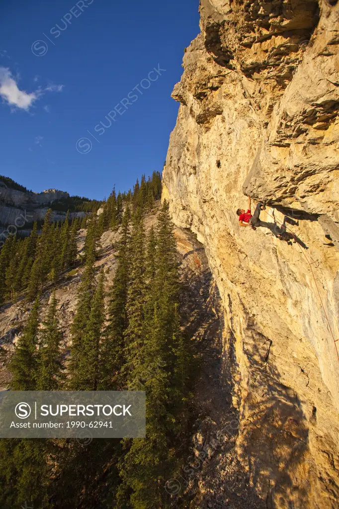 A man climbs the sport route Fire in the Sky 12b at sunset, Echo Canyon, Canmore, Alberta, Canada