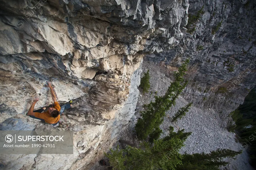 A man sport climbing at sunset on Grotto Mountain. Standard Deviation 11b, Echo Canyon, Canmore, Alberta, Canada