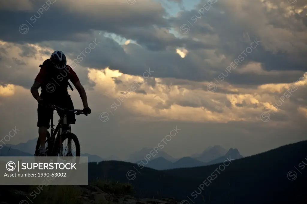 A male mountain biker riding at ridgetop at sunset. Canmore, Alberta, Canada