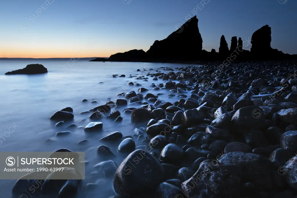 Waves wash over stones near the distinctive rock formation at Cape Split, Bay of Fundy, Nova Scotia,