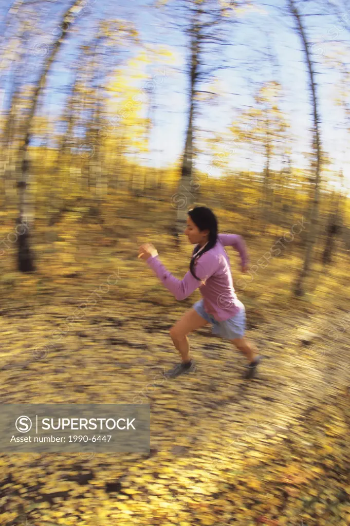 young asian woman trail running below Mt Yamnuska, Kananaskis, Alberta, Canada