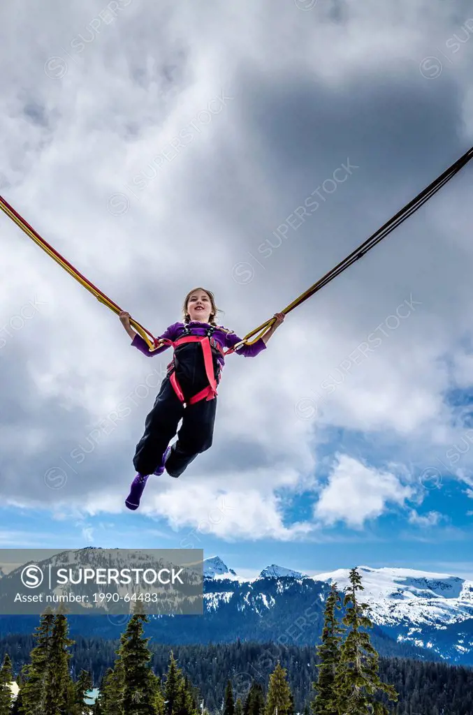 Young girl enjoys the bungy trampoline at Mount Washington, Vancouver Island, British Columbia, Canada