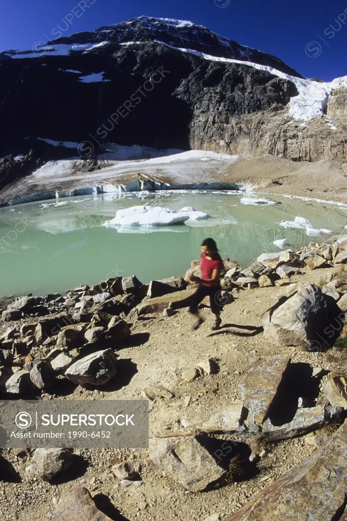 young athletic woman trail running by a glacier melt and lake near Edith Caveal Mountain, Jasper National Park, Alberta, Canada