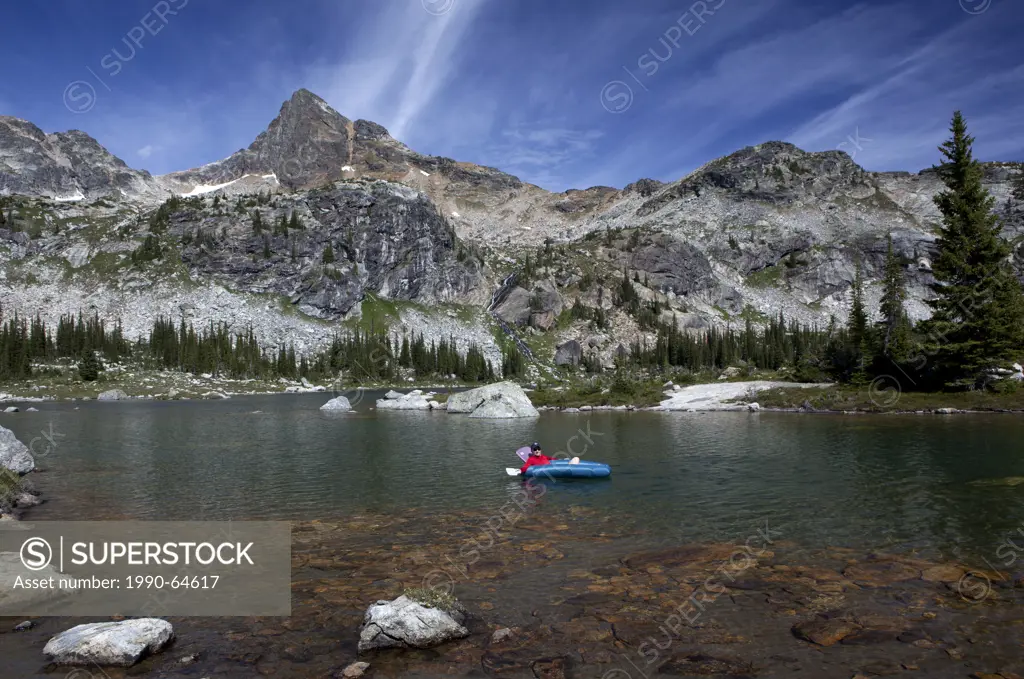 Hiker rafts Gwillim Lakes below Lucifer Peak, Selkirk Mountains, Valhalla Provincial Park, British Columbia, Canada