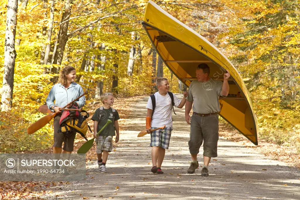 Family portaging canoe, Algonquin Park, Ontario, Canada.