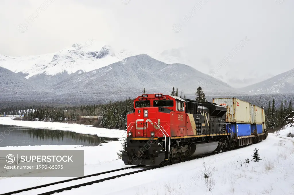 A Canadian National freight train pulling a load of containers along the Athabasca river near the hamlet of Brule on a snowy winters day in the rockey...