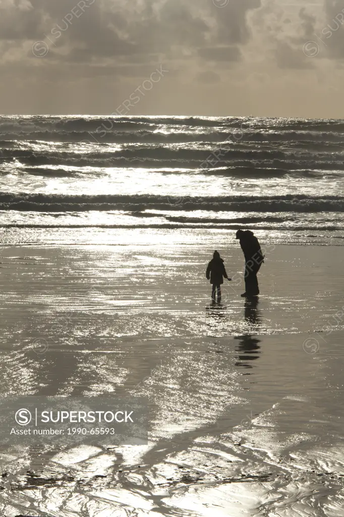 A father and daughter on Cox Bay beach near Tofino, British Columbia, Canada on Vancouver Island in Clayoquot Sound UNESCO Biosphere Reserve.