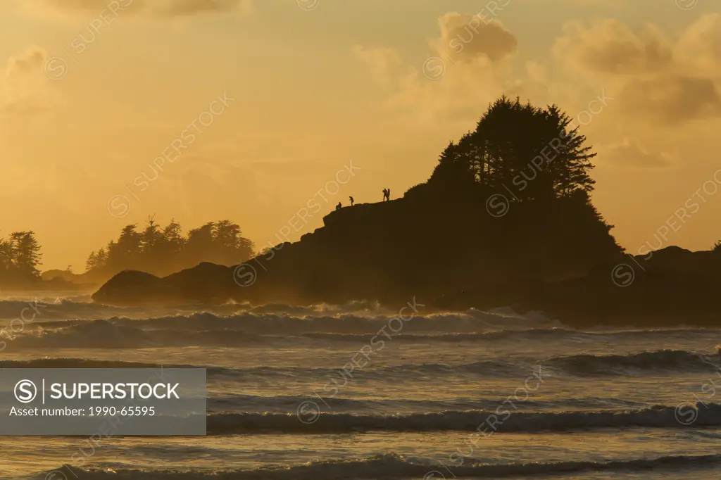 People stand on the rocks at Sunset Point at Cox Bay beach near Tofino, British Columbia, Canada on Vancouver Island in Clayoquot Sound UNESCO Biosphe...