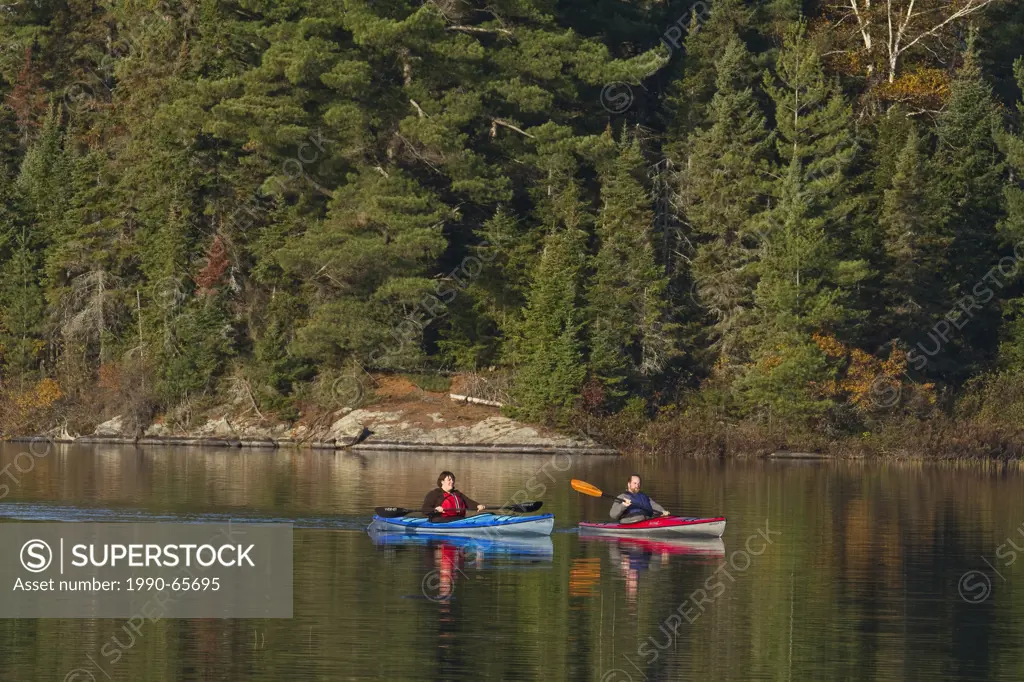 Middle_aged couple enjoy early morning paddle in kayaks on Source Lake, Algonquin Park, Ontario, Canada.