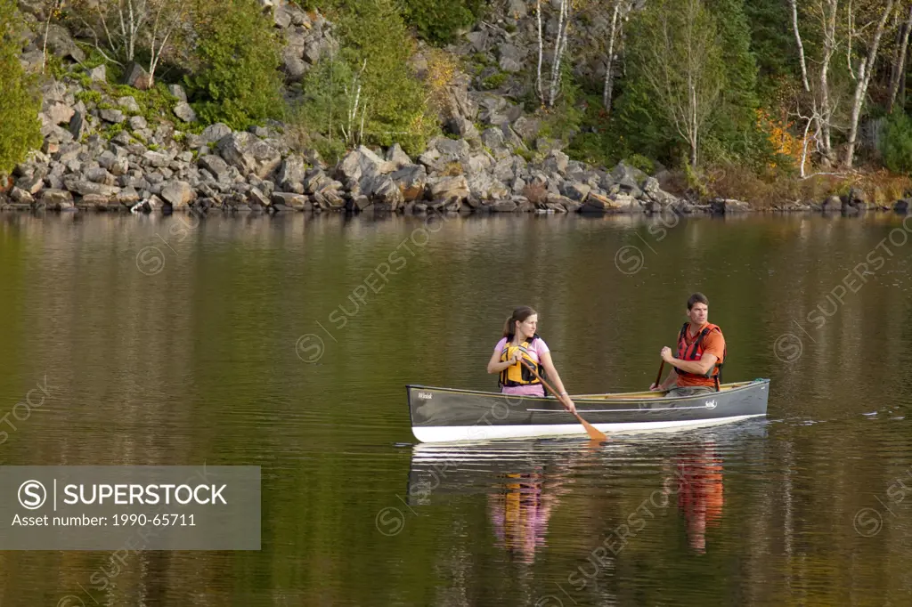 Young couple canoe on Oxtongue Lake, Muskoka, Ontario, Canada.