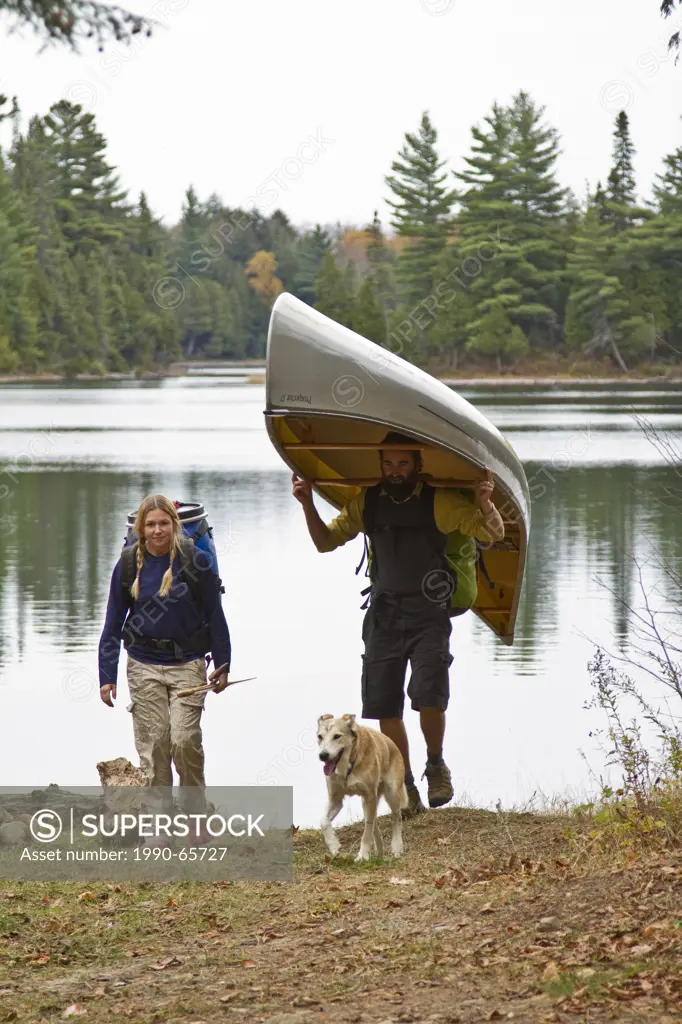 Young couple portage canoe from small lake in northwestern end of Algonquin Park, Ontario, Canada.