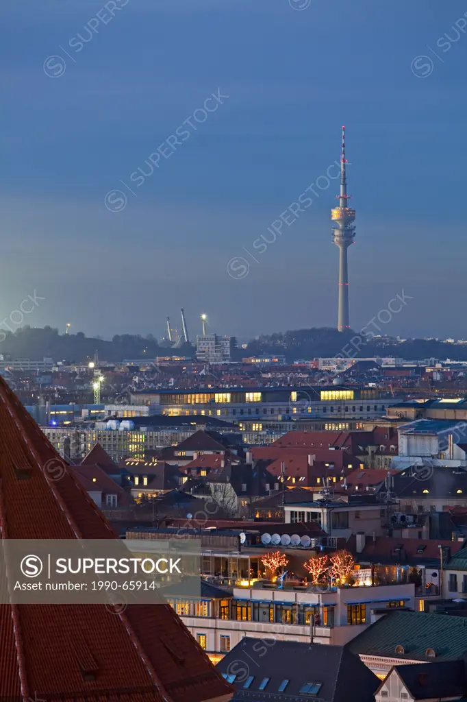 View towards the Olympiaturm Olympic Tower over the rooftops of buildings at sunset in the City of München Munich Bavaria, Germany, Europe.