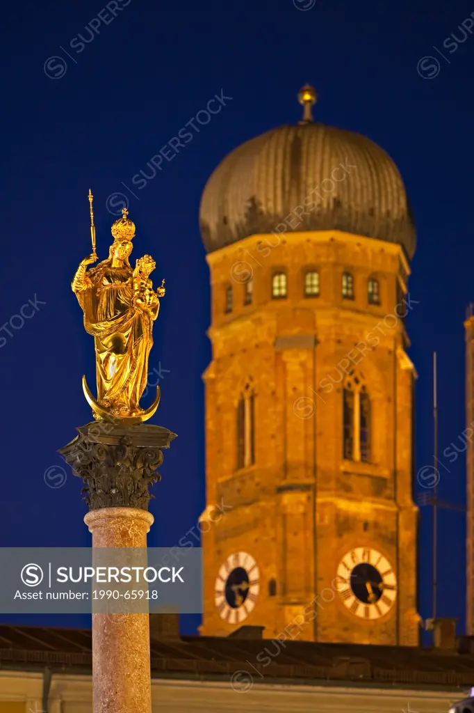 Golden statue of the Virgin Mary atop the Mariensäule in the Marienplatz with a tower of the Frauenkirche, Cathedral of our Blessed Lady in the backgr...