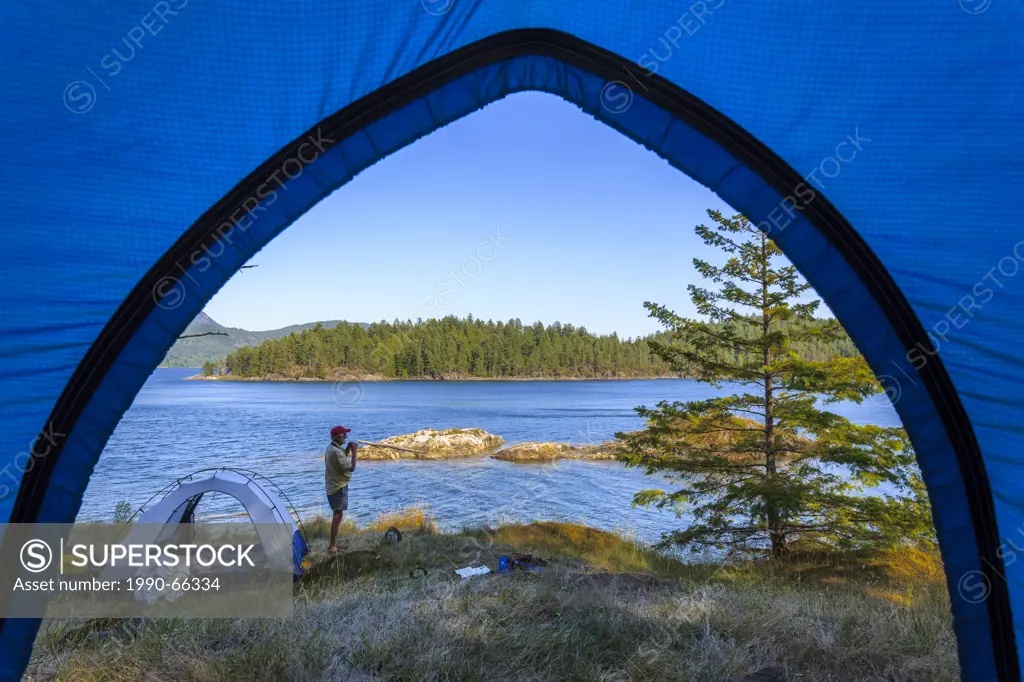 A kayaker watching for whales while camped on Penn Island in Sutil Channel between Read and Cortes Islands British Columbia, Canada