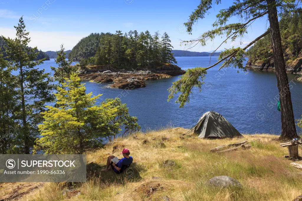 A kayaker relaxes on Penn Island in Sutil Channel between Read and Cortes Islands British Columbia Canada. Model Released