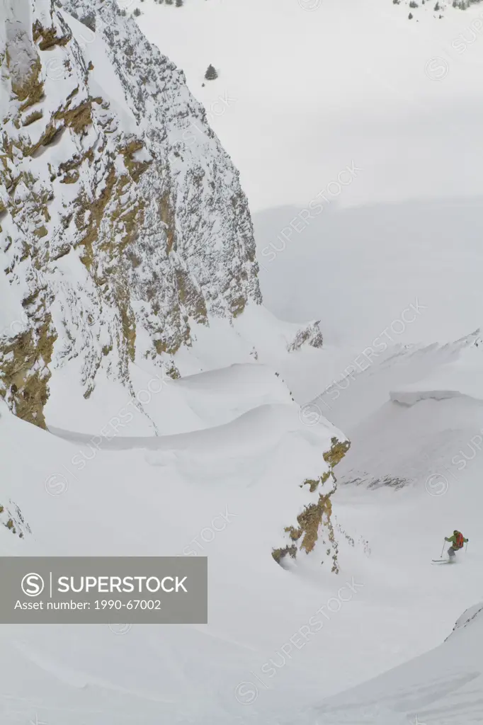 A male backcountry skier descends a steep, exposed coulior on Mt. Chester, AB