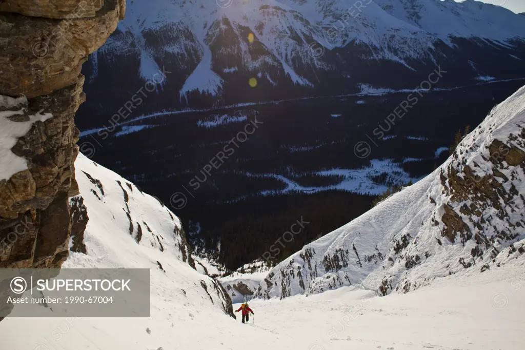 A male backcountry skier bootpacks up a steep and exposed coulior on Mt. Patterson, Icefields Parkway, Banff, AB