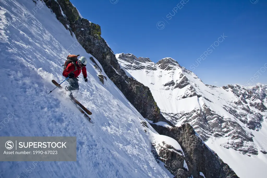 A male backcountry skier on tele skis descends a steep couloir with a unique limestone arch in it. Mt. French, Peter Lougheed Provincial Park, Kananas...