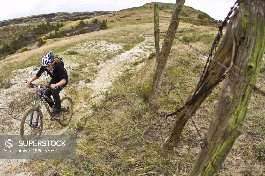 A female mountain biker follows a perfect ribbon of singletrack. Maah Daah Hey Trail, North Dakota